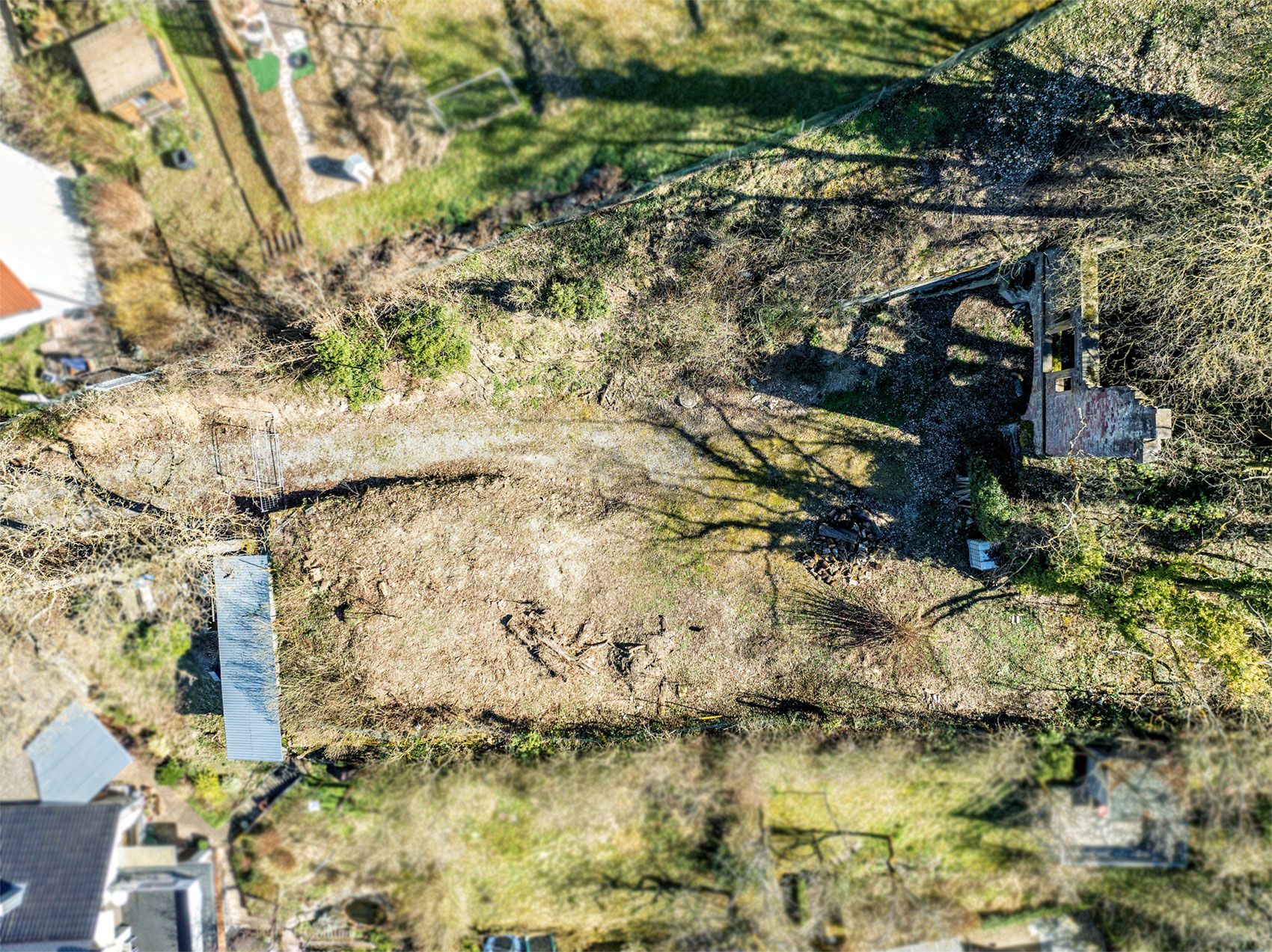 Luftaufnahme eines länglichen Gartengrundstücks mit Bäumen und einem kleinen Schuppen.