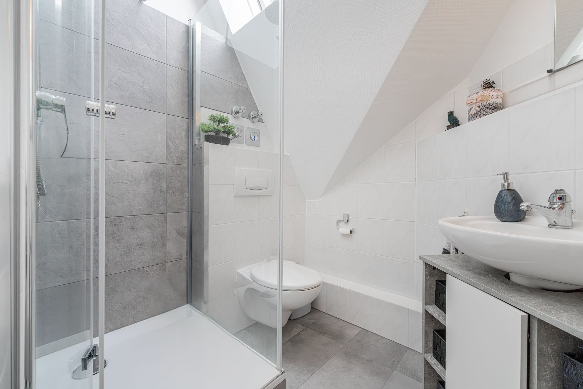 Modernes Badezimmer mit Dusche, WC und Waschbecken unter einer Dachschräge.