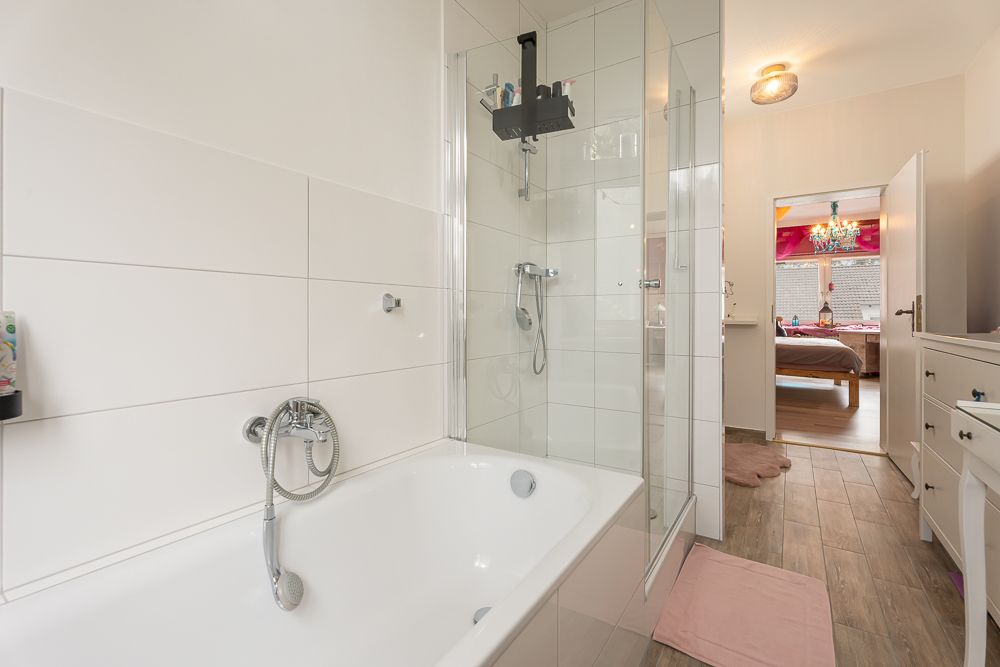 Modernes Badezimmer mit Badewanne, Dusche und Blick ins Schlafzimmer.