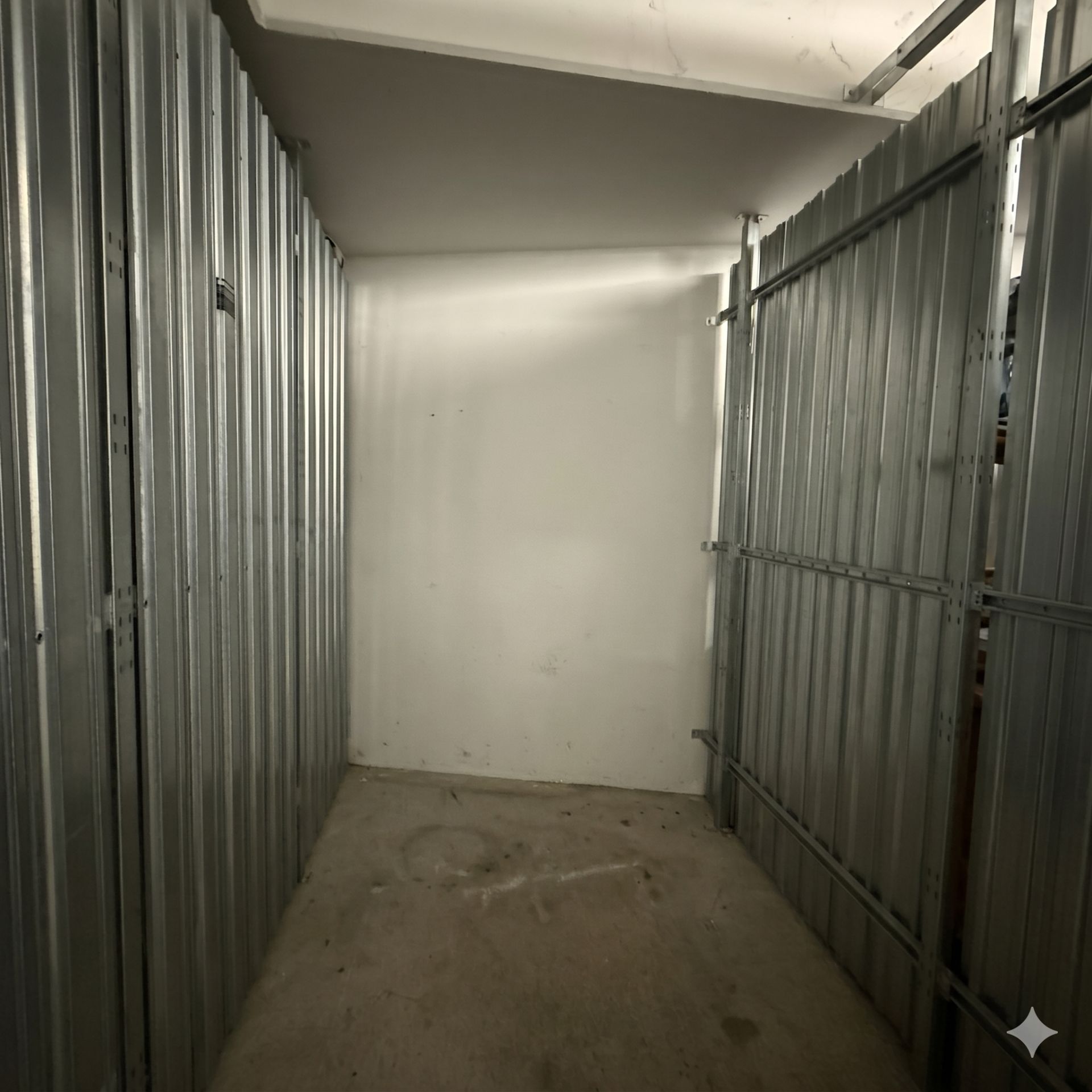 Leerer Abstellraum mit Metallwänden und Betonboden.
