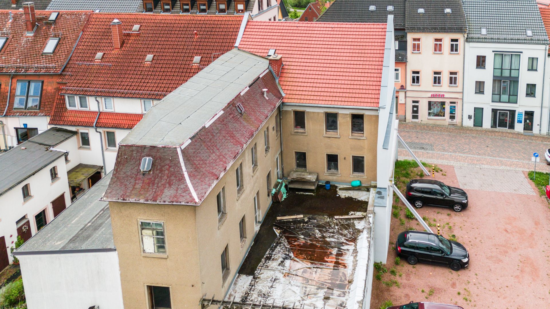 Mehrstöckiges Wohnhaus mit Innenhof und parkenden Autos, aufgenommen aus der Vogelperspektive.