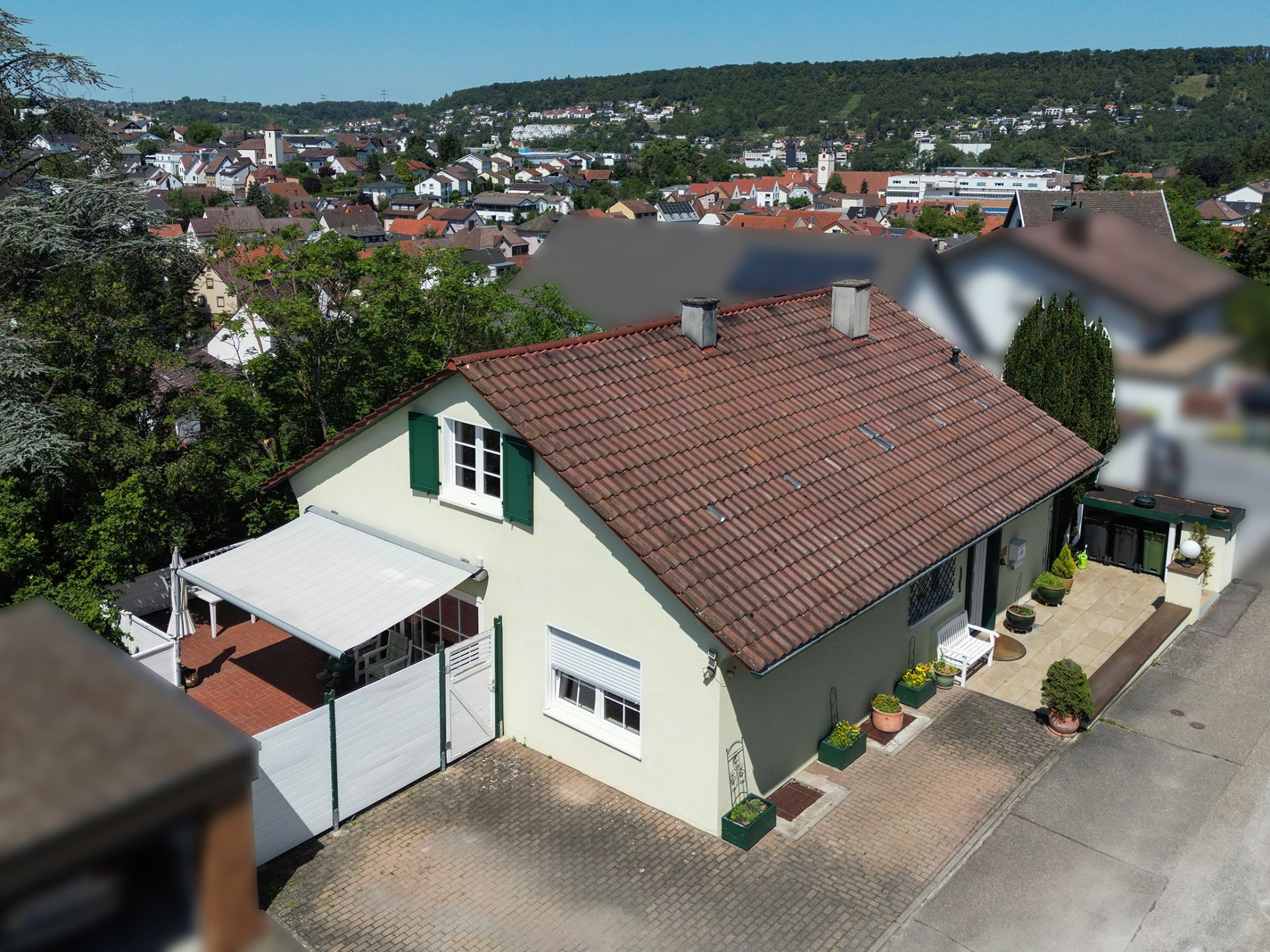 Einfamilienhaus mit rotem Dach, Terrasse und bepflanztem Eingang in Wohngebiet.