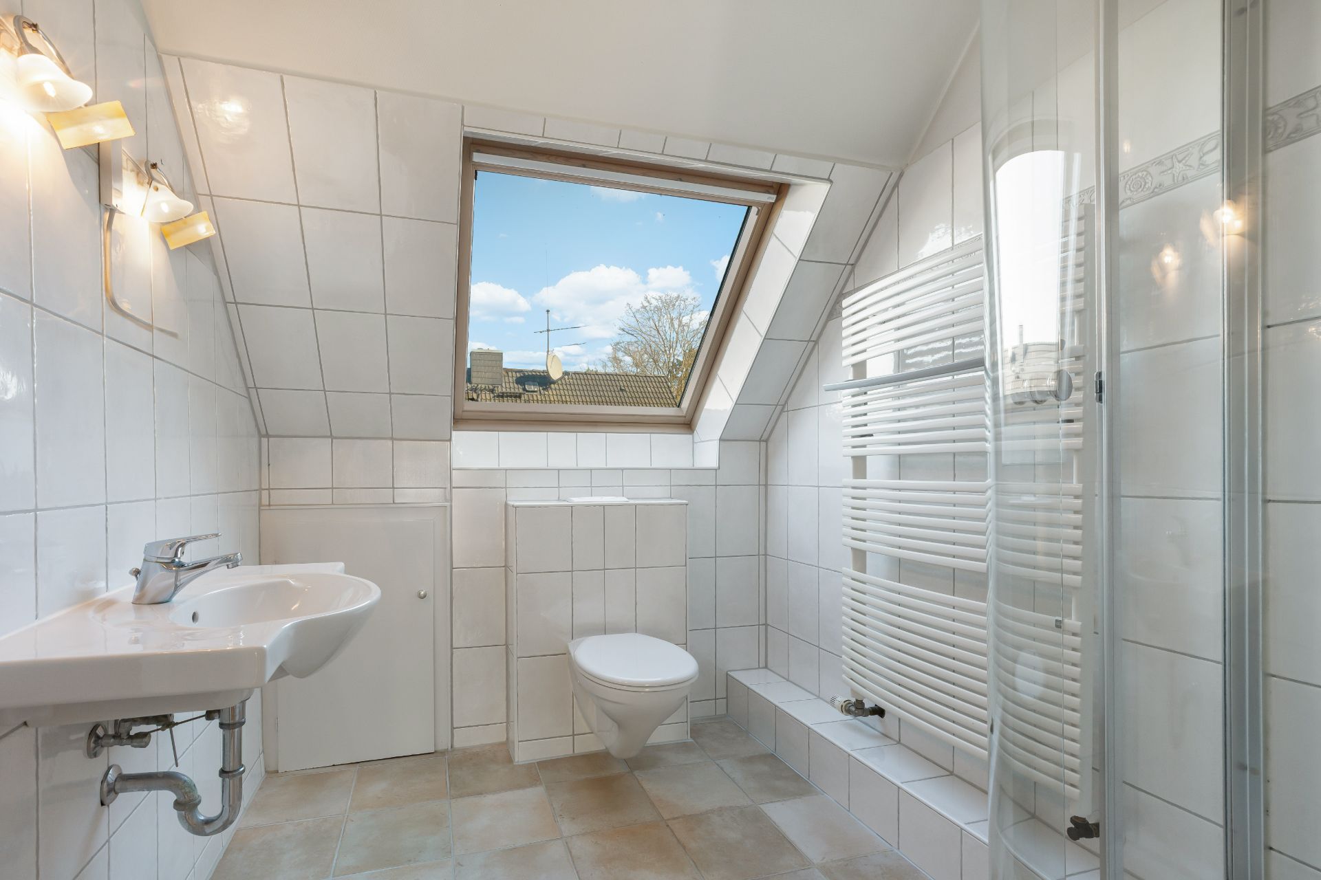 Helles Badezimmer mit Dachfenster, Waschbecken, WC, Handtuchheizkörper und Dusche.