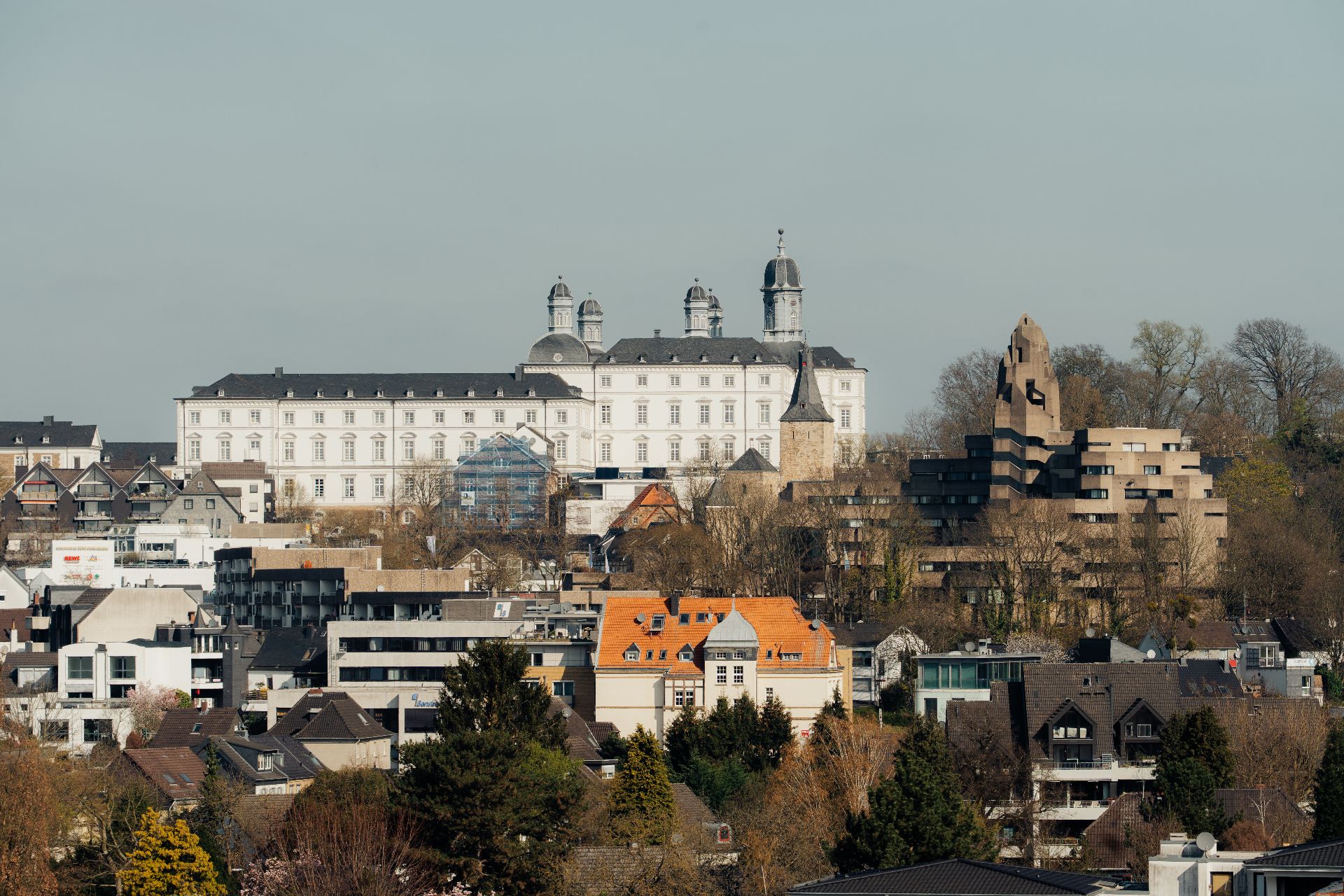 Stadtansicht mit verschiedenen Wohnhäusern und einem großen weißen historischen Gebäude im Hintergrund.