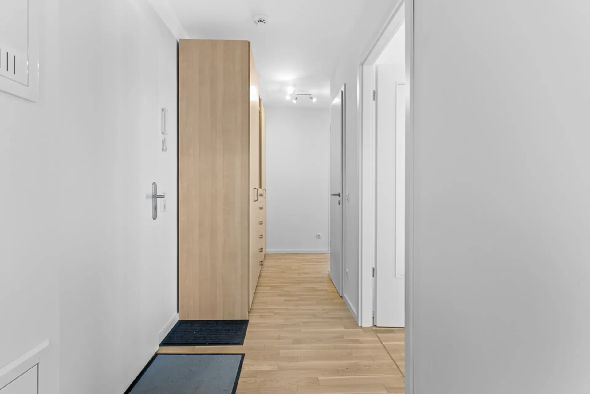 Heller Flur mit Holzboden, Garderobenschrank und mehreren Türen in einer Wohnung.