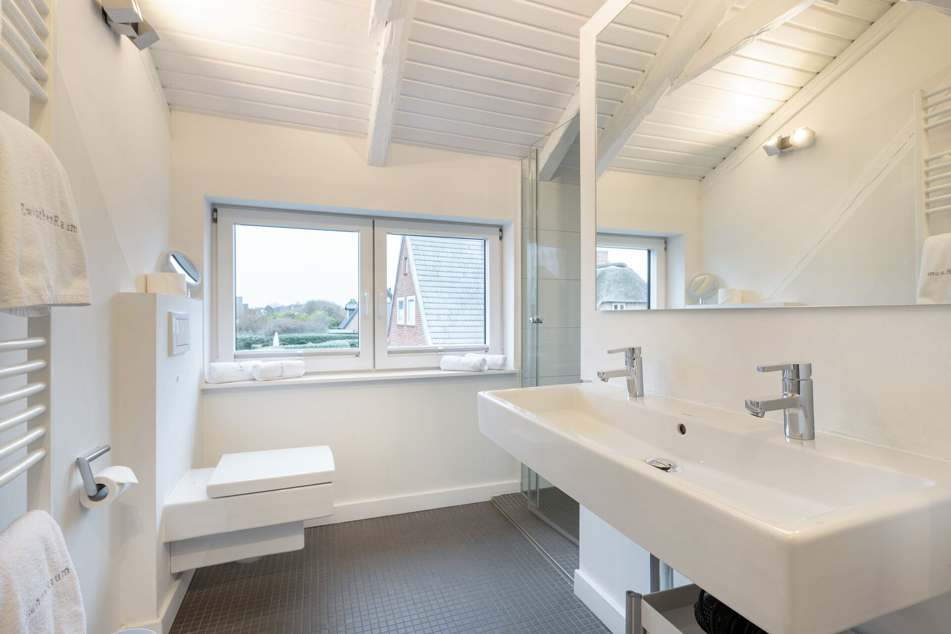 Modernes Badezimmer mit Doppelwaschbecken, großem Spiegel, Dusche und Fenster, helle Einrichtung.