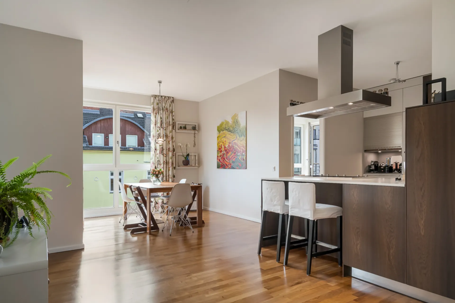 Helle Wohnküche mit Essbereich, modernem Herd, Holzboden und großen Fenstern.