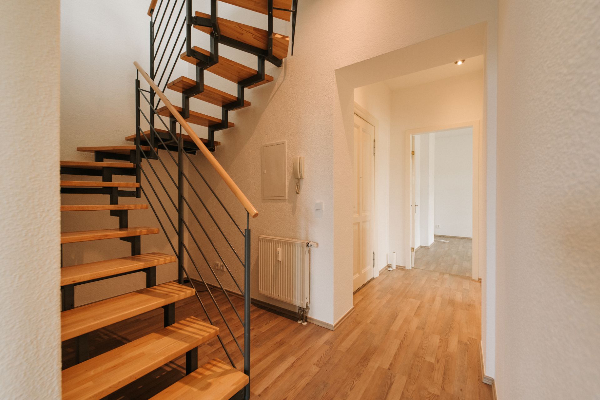 Heller Flur mit Holztreppe und Holzfußboden in einer Wohnung.