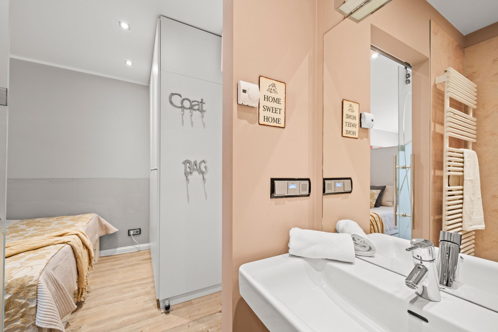Helles Badezimmer mit Doppelwaschbecken, Handtuchwärmer und Blick ins Schlafzimmer.