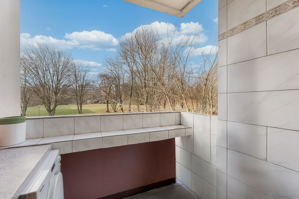 Gefliester Balkon mit Blick auf Bäume und eine Wiese.