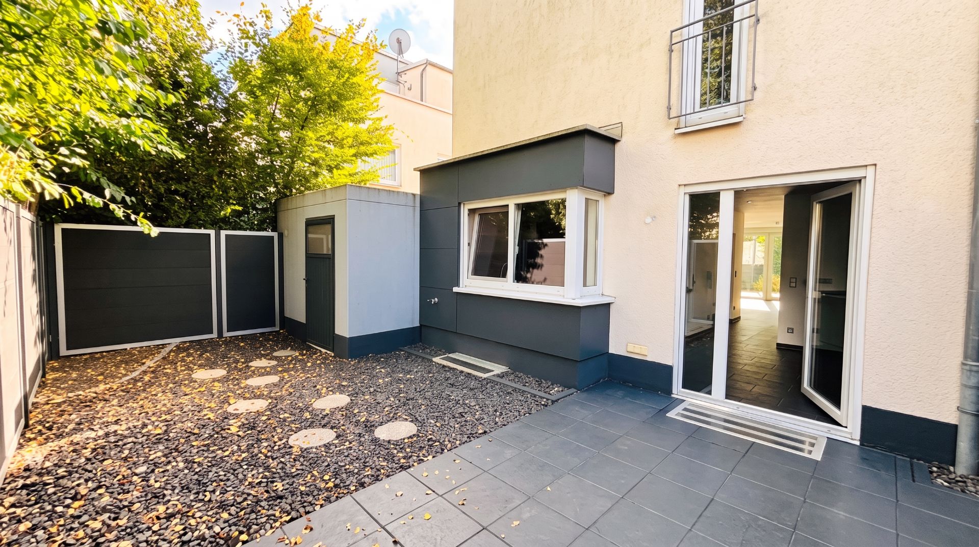 Kleiner, gepflasterter Innenhof mit Steinen, Nebengebäude und Zugang zu einem Wohnraum.