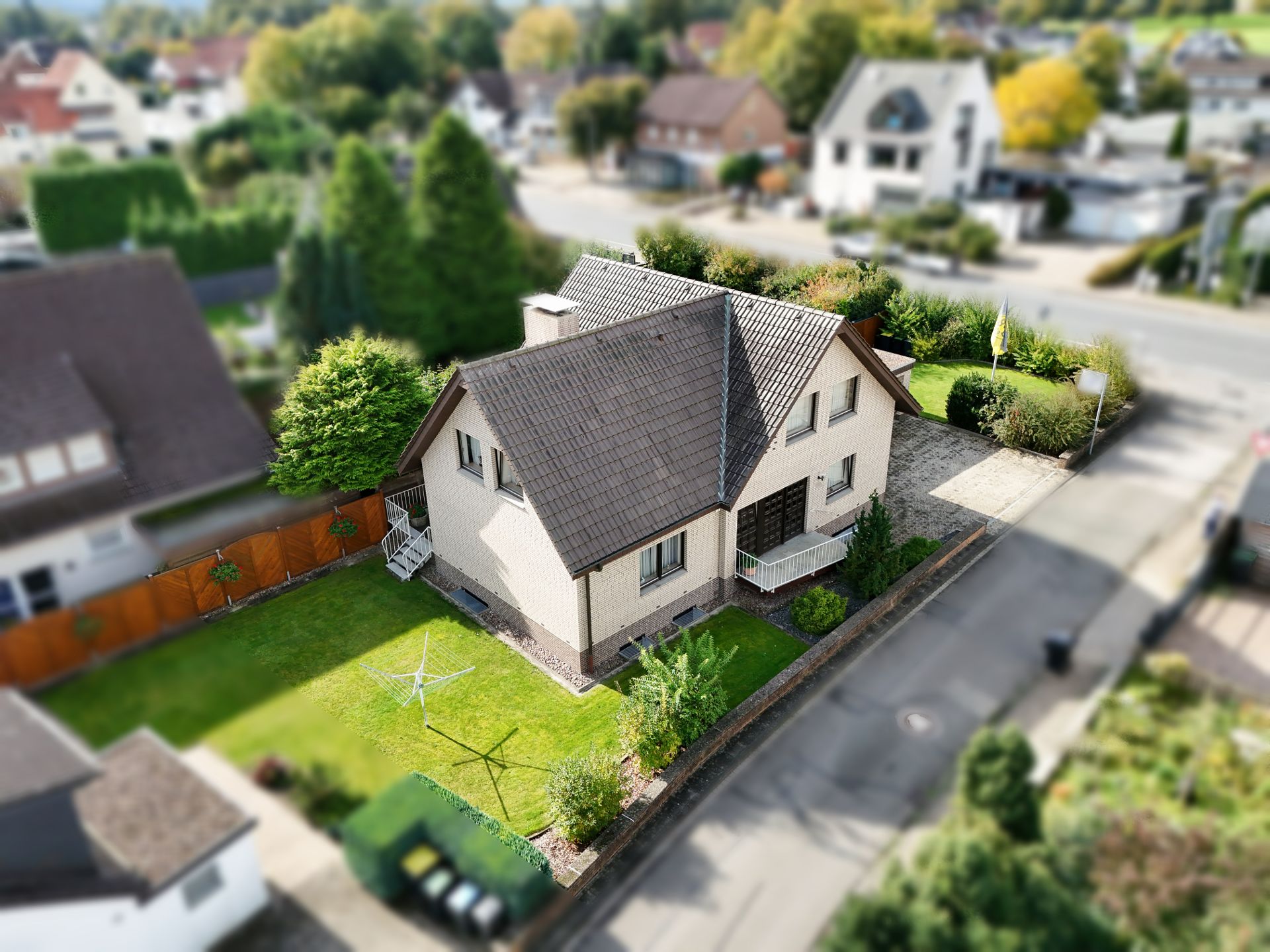 Einfamilienhaus mit Garten und kleinem Vorgarten an einer Wohnstraße.