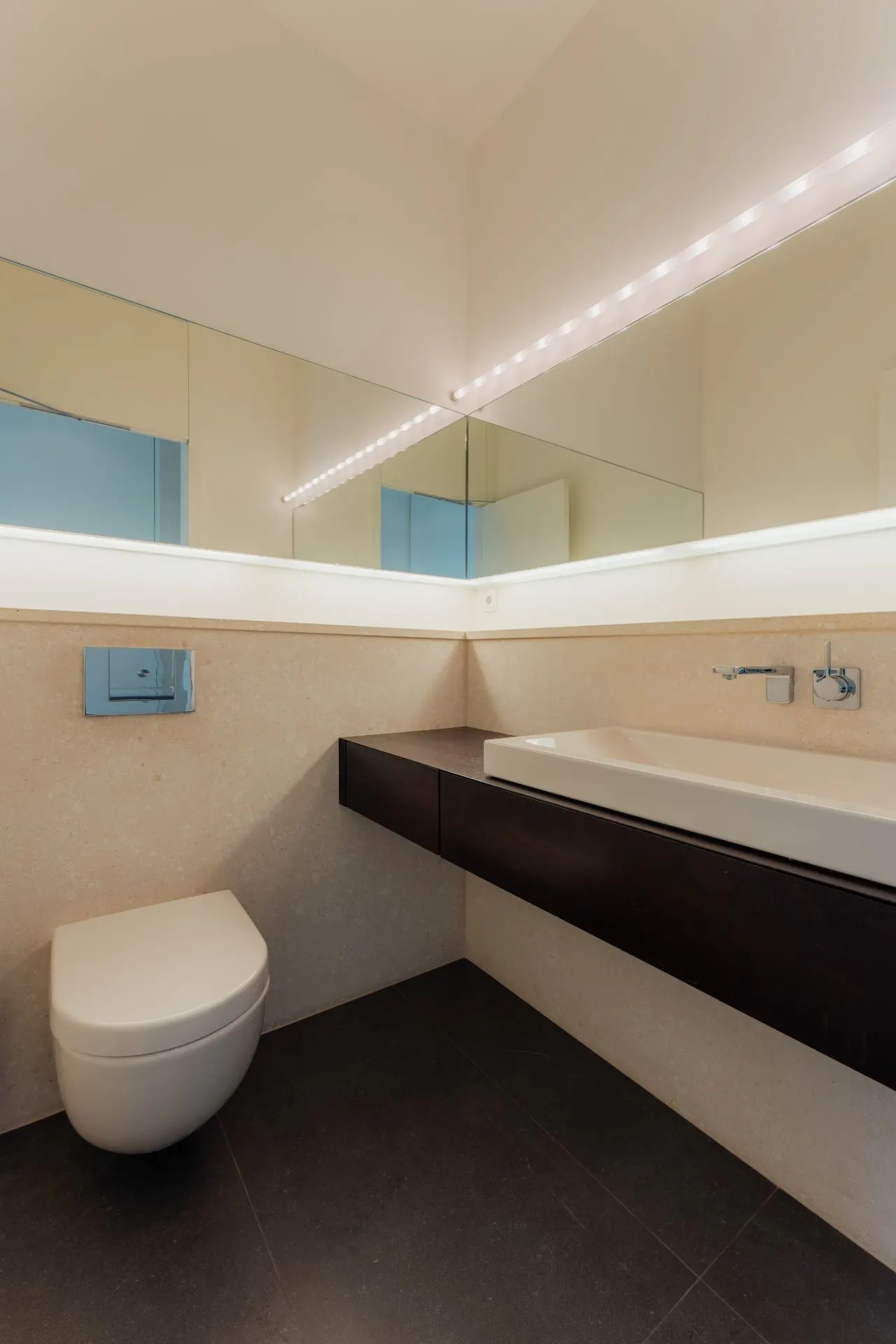 Modernes Badezimmer mit Wandtoilette, großem Spiegel und rechteckigem Waschbecken.