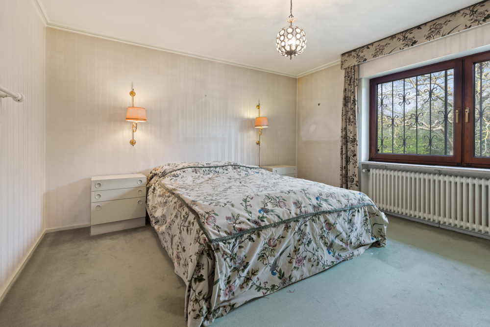 Schlafzimmer mit Doppelbett, zwei Nachttischen und großem Fenster mit Blick ins Grüne.