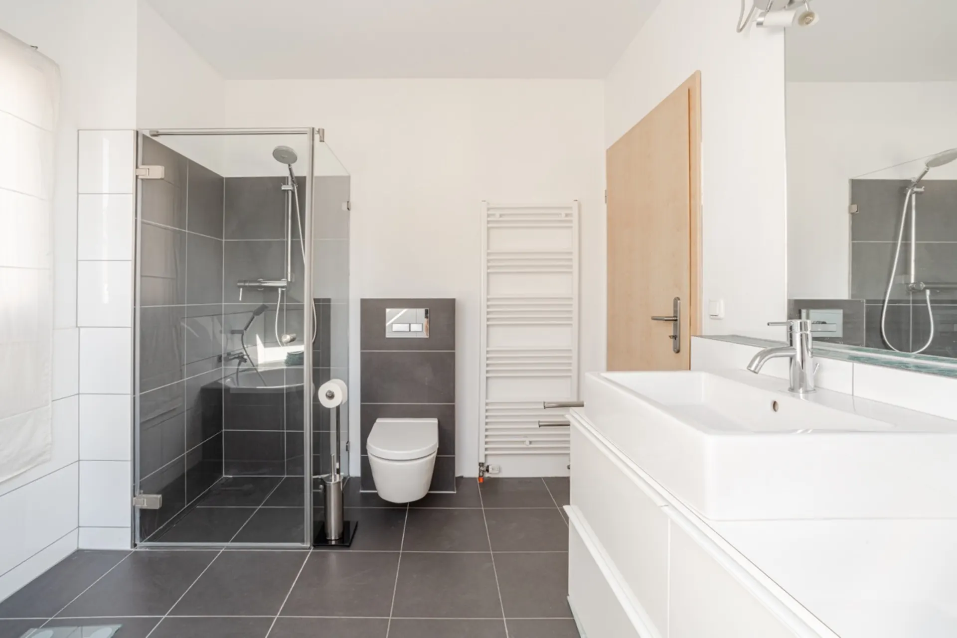 Modernes Badezimmer mit ebenerdiger Dusche, Wandtoilette und Doppelwaschbecken.