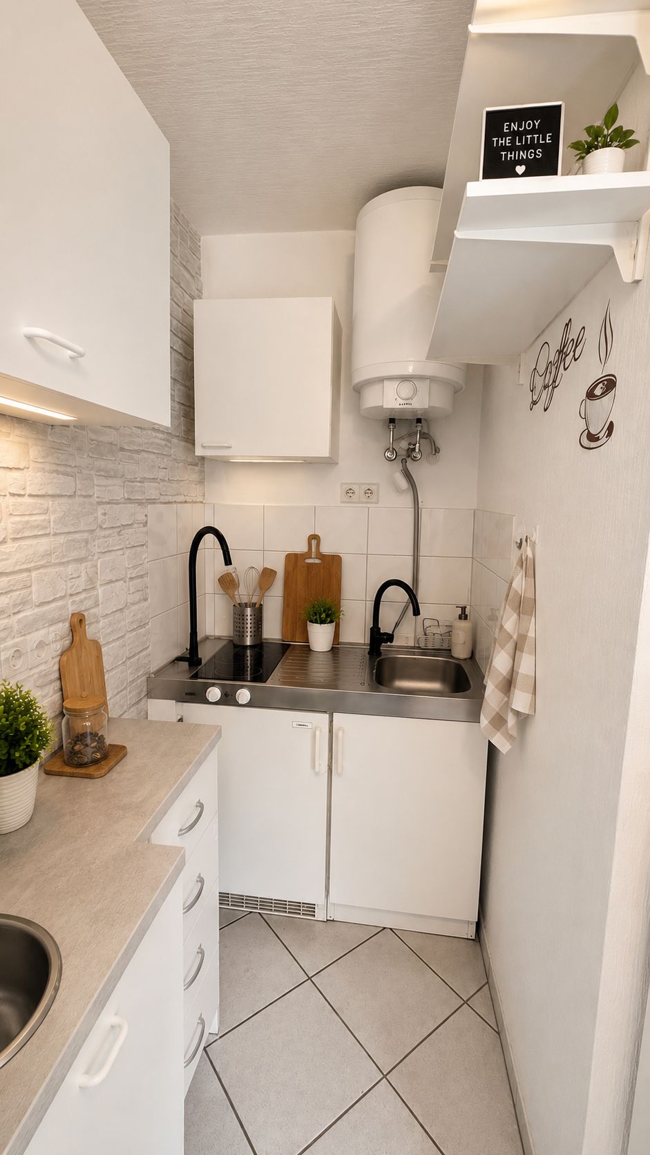 Kleine moderne Küche mit weißen Schränken, Spüle, Herd und Dekoration.