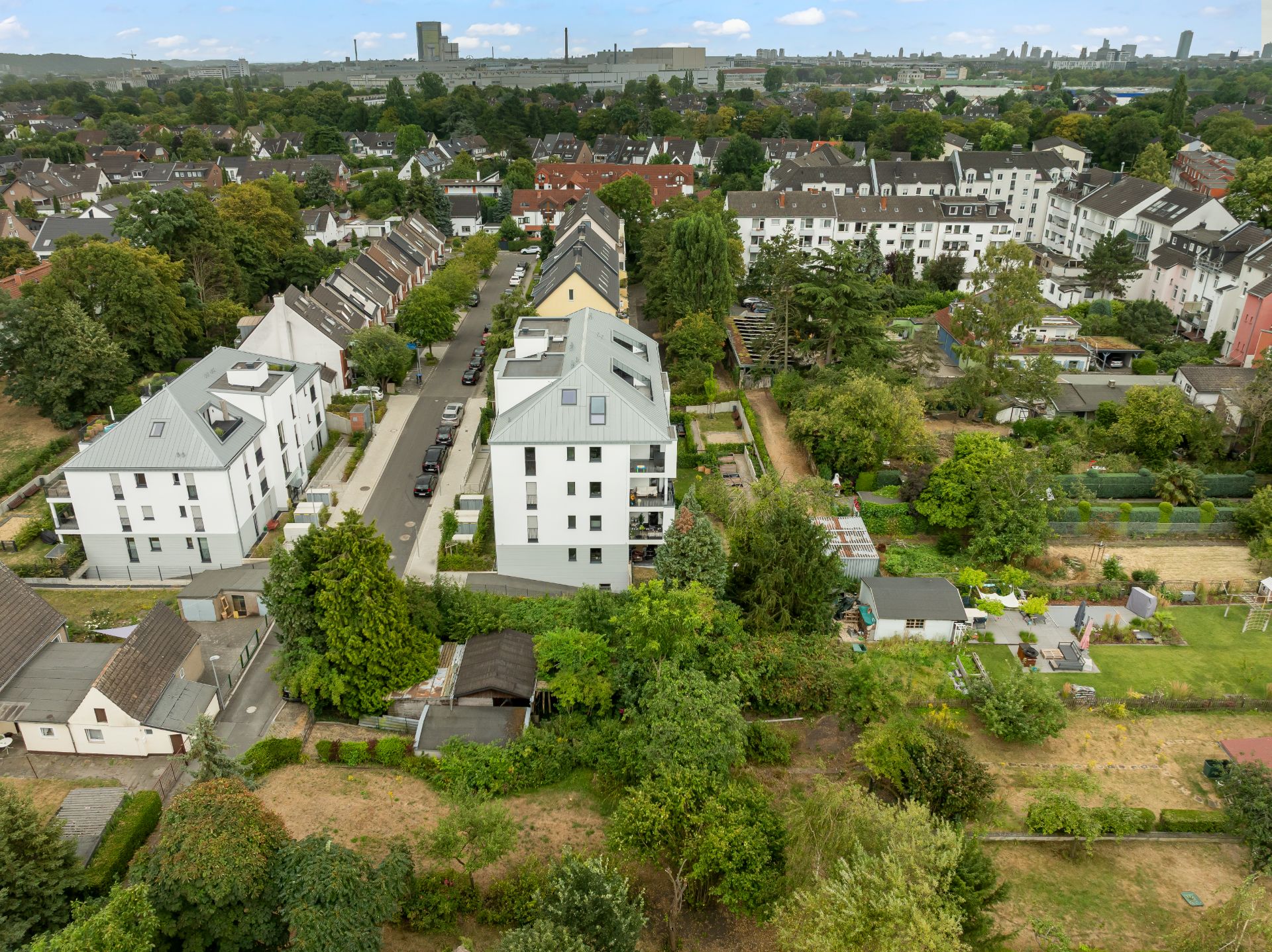 Luftaufnahme eines Wohngebiets mit mehrstöckigen Gebäuden, Straßen und viel Grün.