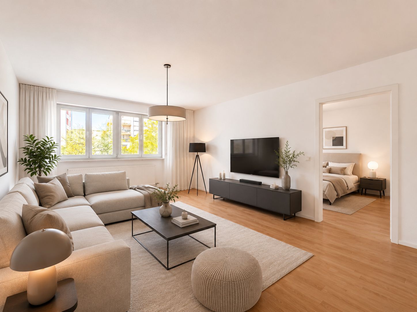 Modernes Wohnzimmer mit großem Sofa, TV, Couchtisch und Blick ins Schlafzimmer.