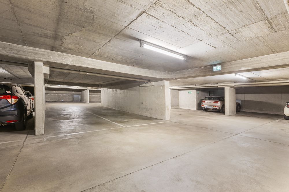 Helle Tiefgarage mit Betonwänden und mehreren parkenden Autos.