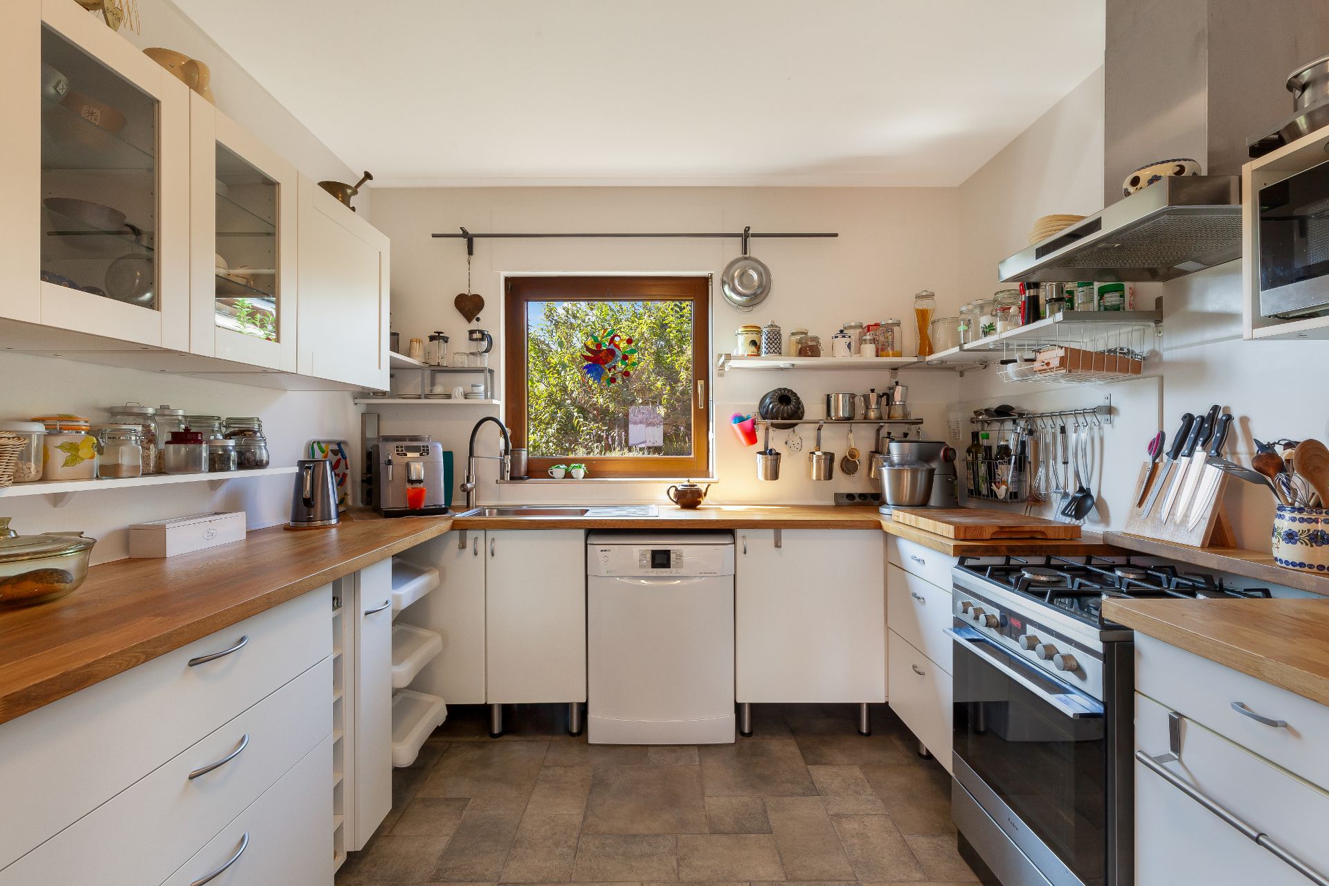 Moderne Küche mit Holzarbeitsplatten, Gasherd, Spüle, Geschirrspüler und Küchenutensilien.