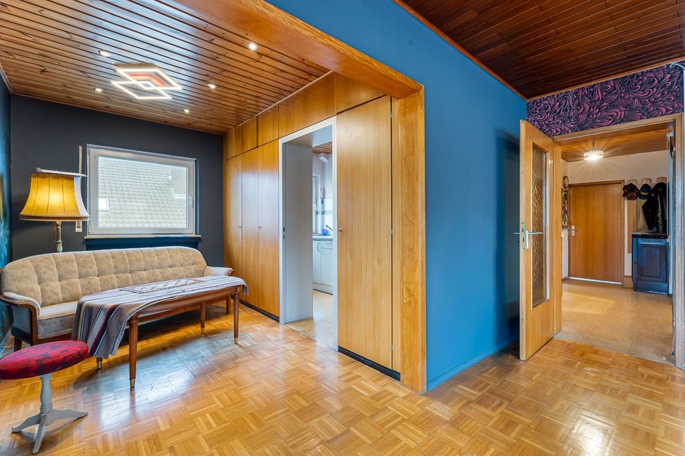 Wohnzimmer mit Holzdecke, Sofa, Stehlampe, Tisch und blauer Wand.