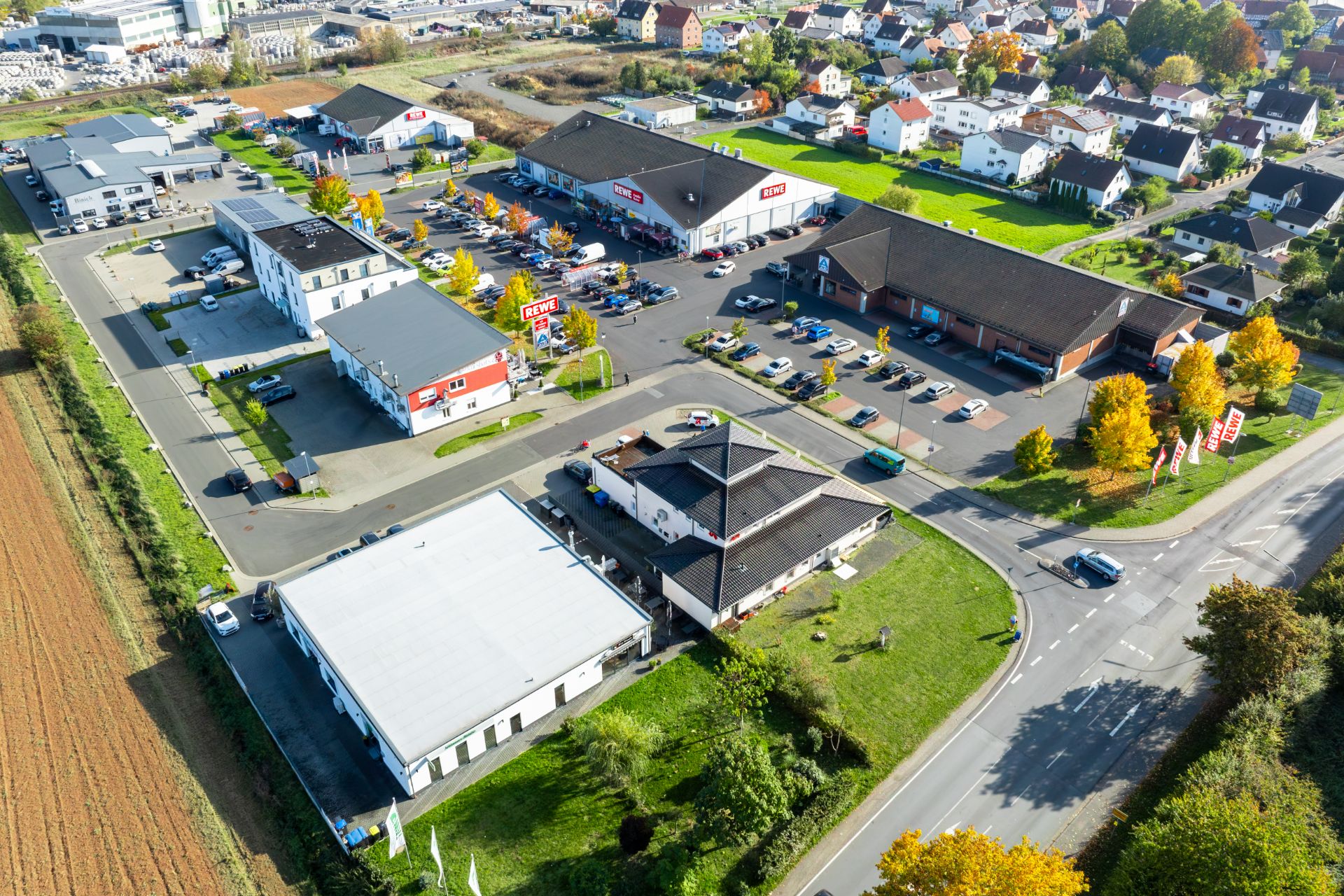 Luftaufnahme eines Wohngebiets mit mehreren Gebäuden, Parkplätzen und Straßen.