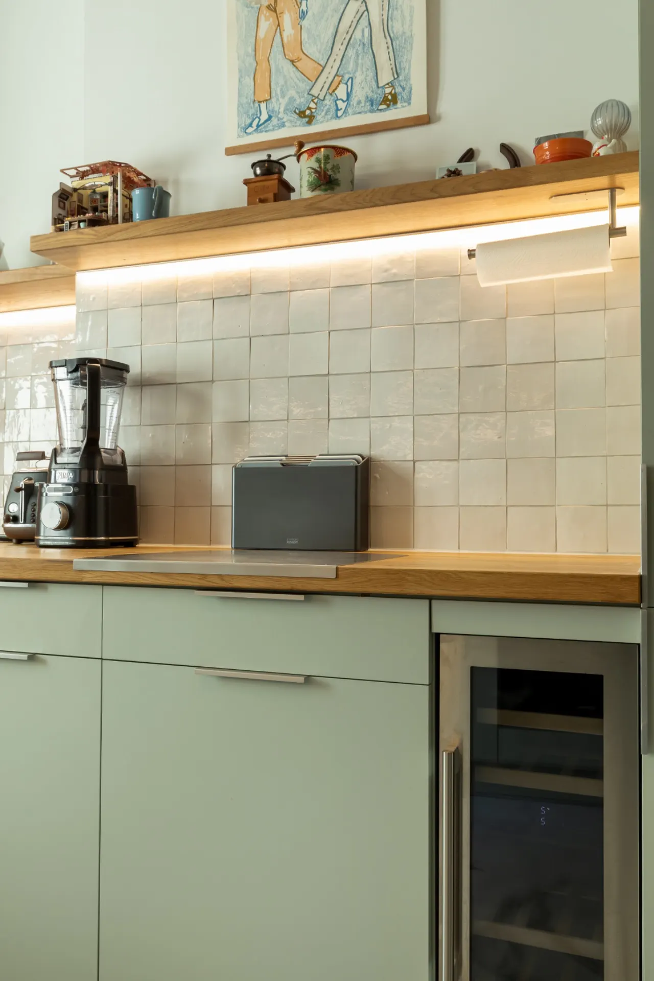 Moderne Küchentheke mit Mixer, Brotkasten und Kühlschrank unter Holzregal.