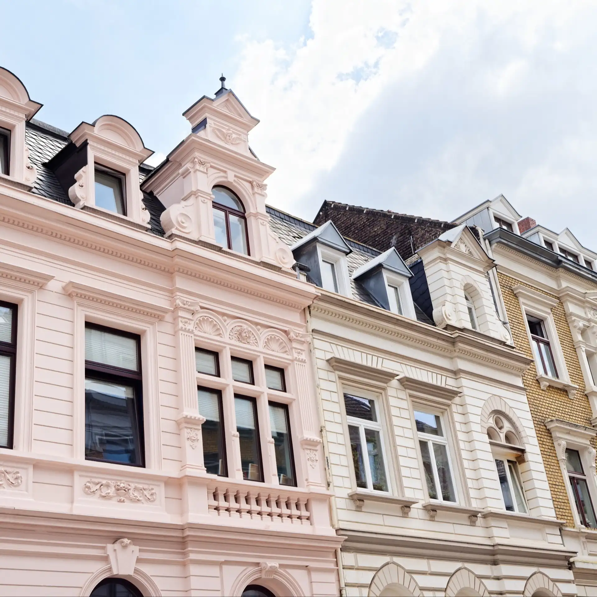 Reihen von historischen Wohnhäusern mit verzierter Fassade und mehreren Fenstern.