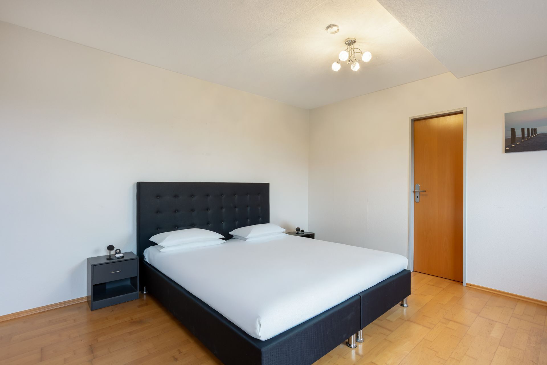 Schlafzimmer mit Doppelbett, zwei Nachttischen und Holzboden.