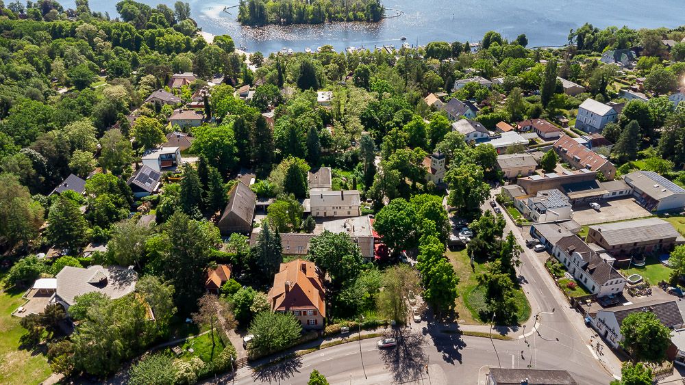 Luftaufnahme eines Wohngebiets mit vielen Häusern und Bäumen in Seenähe.