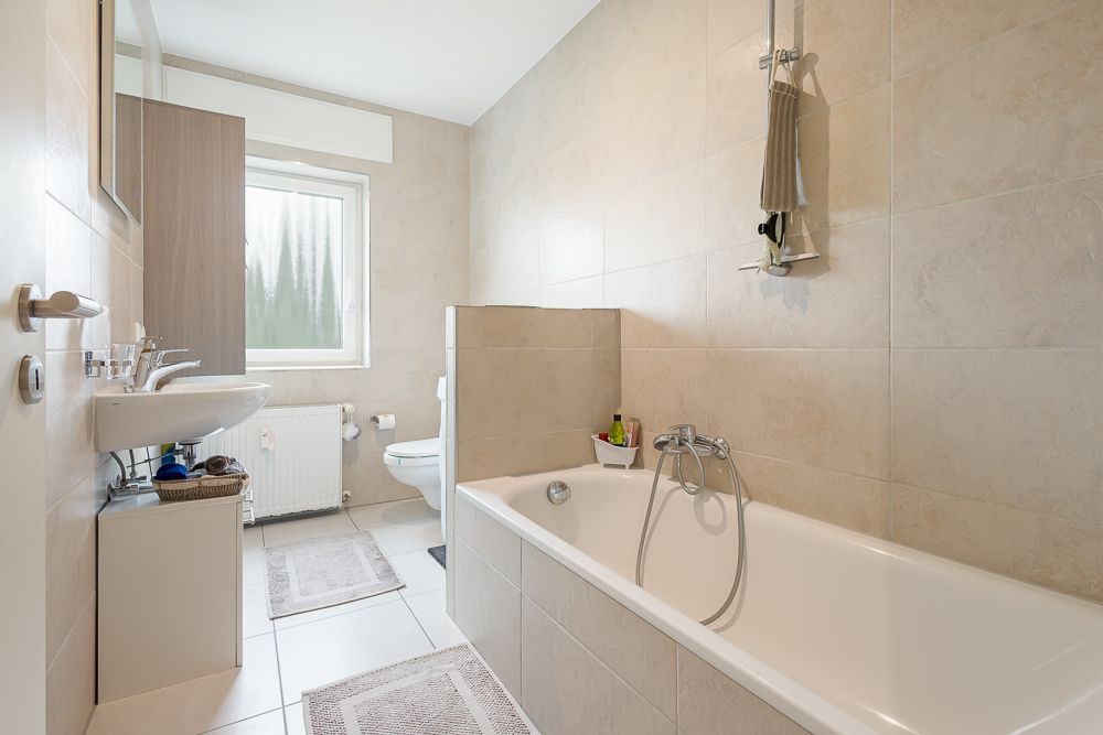 Helles Badezimmer mit Badewanne, Waschbecken, Toilette und Fenster.