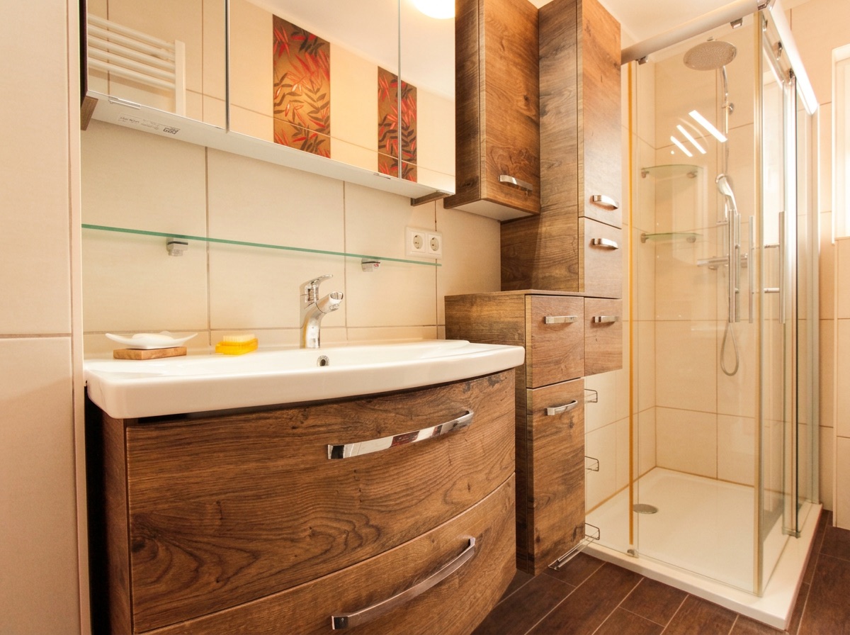Modernes Badezimmer mit Holzmöbeln, Waschbecken und Glasdusche.