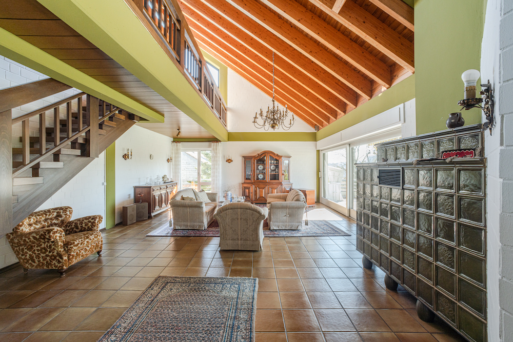 Großes Wohnzimmer mit Sitzgruppe, Kamin, Treppe und offener Galerie unter Holzdecke.