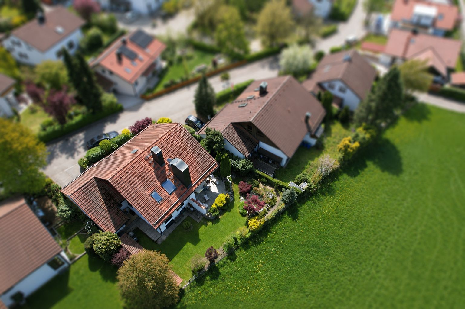 Luftaufnahme eines Einfamilienhauses mit Garten in einer Wohnsiedlung.