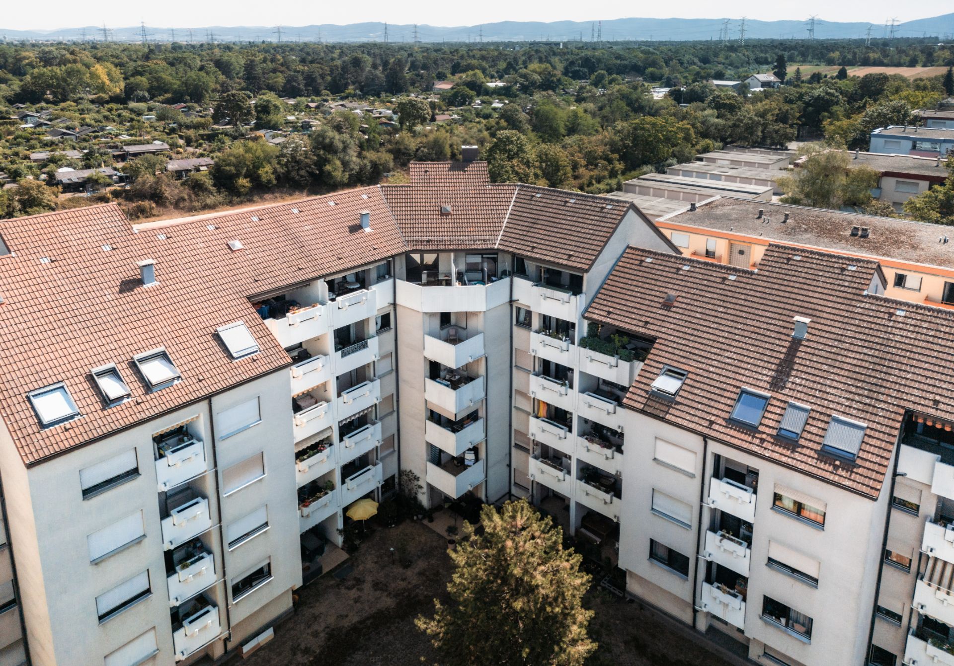 Luftaufnahme eines mehrstöckigen Wohnhauses mit Balkonen und rotem Dach.