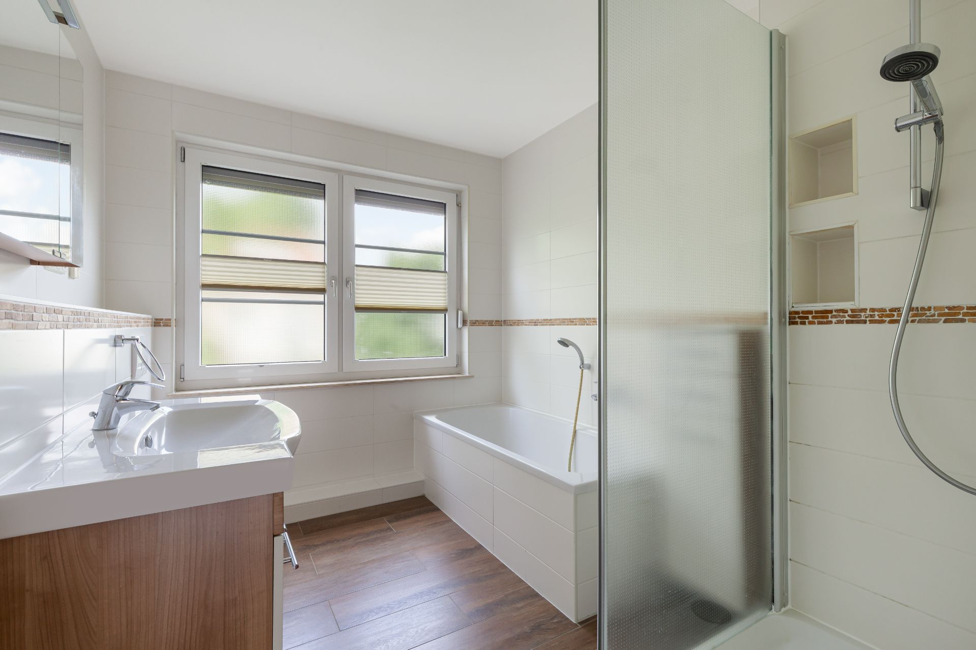 Modernes Badezimmer mit Badewanne, Dusche, Waschbecken und großem Fenster.