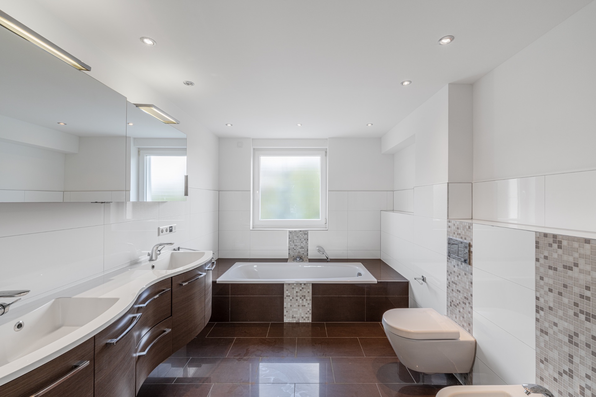 Modernes Badezimmer mit Doppelwaschbecken, Badewanne, WC und Bidet, großes Fenster in der Mitte.