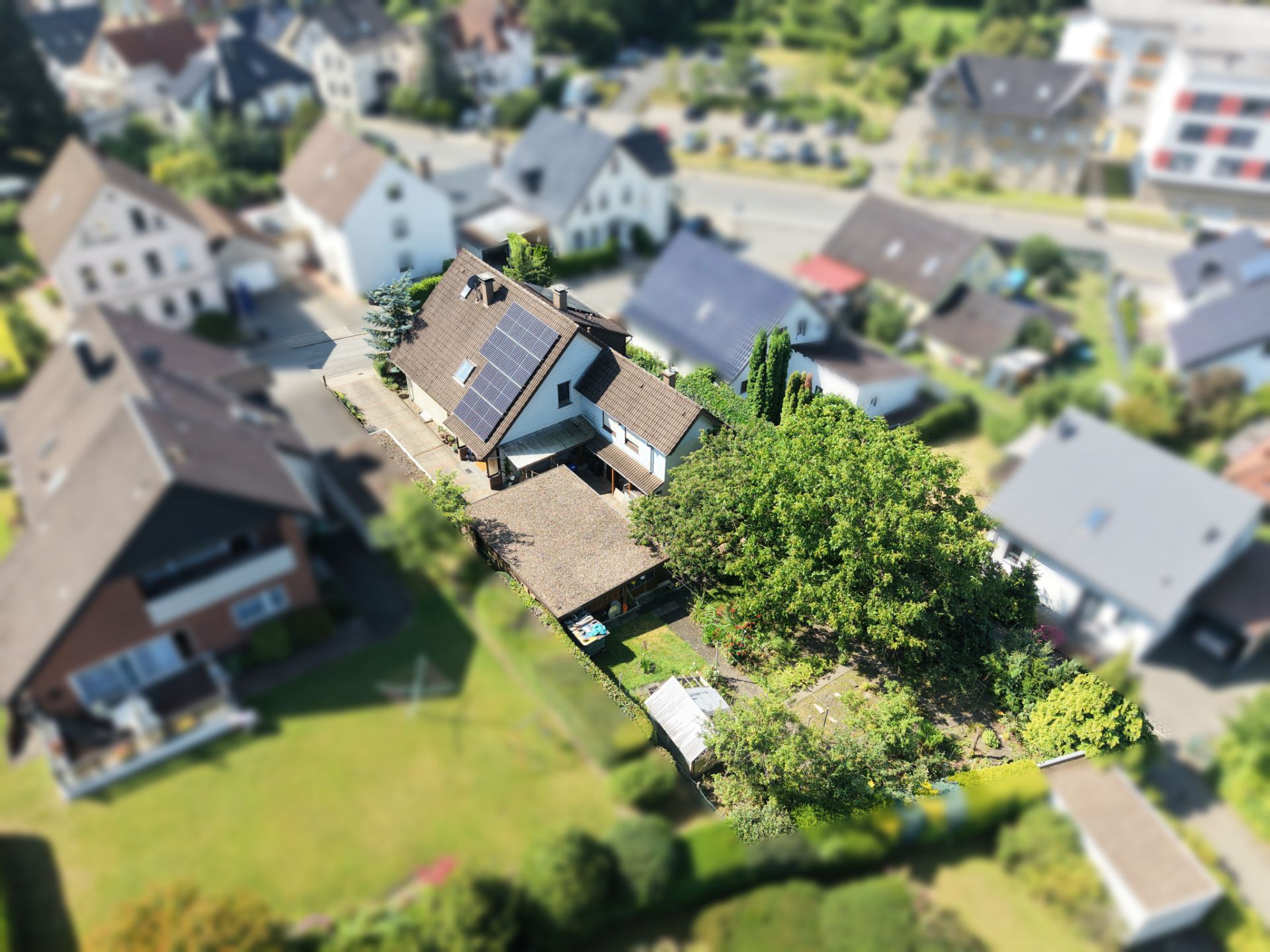 Luftaufnahme eines Einfamilienhauses mit Garten und Solarpanelen auf dem Dach.