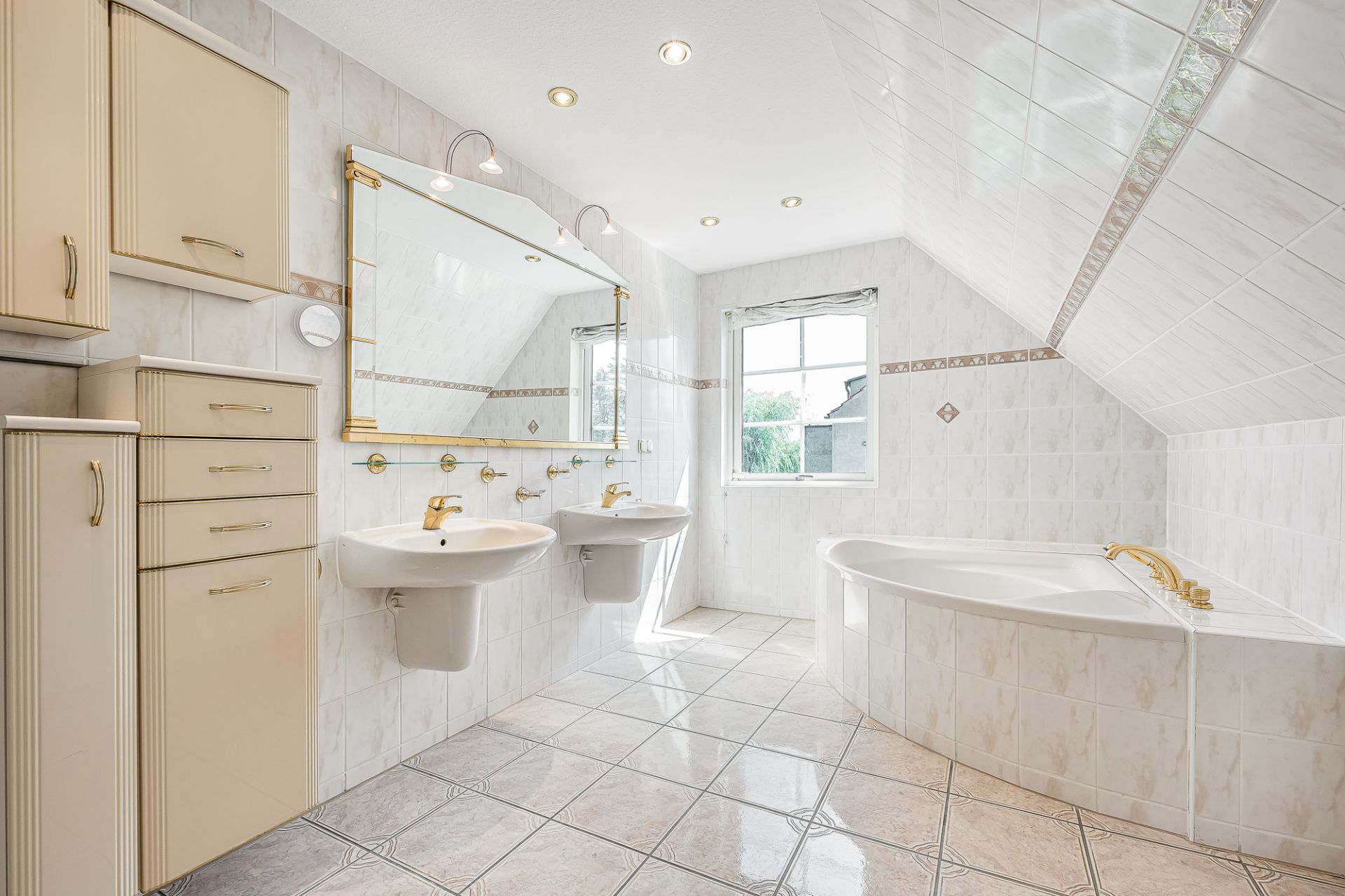 Helles Badezimmer mit zwei Waschbecken, großem Spiegel, Badewanne und Fenstern.