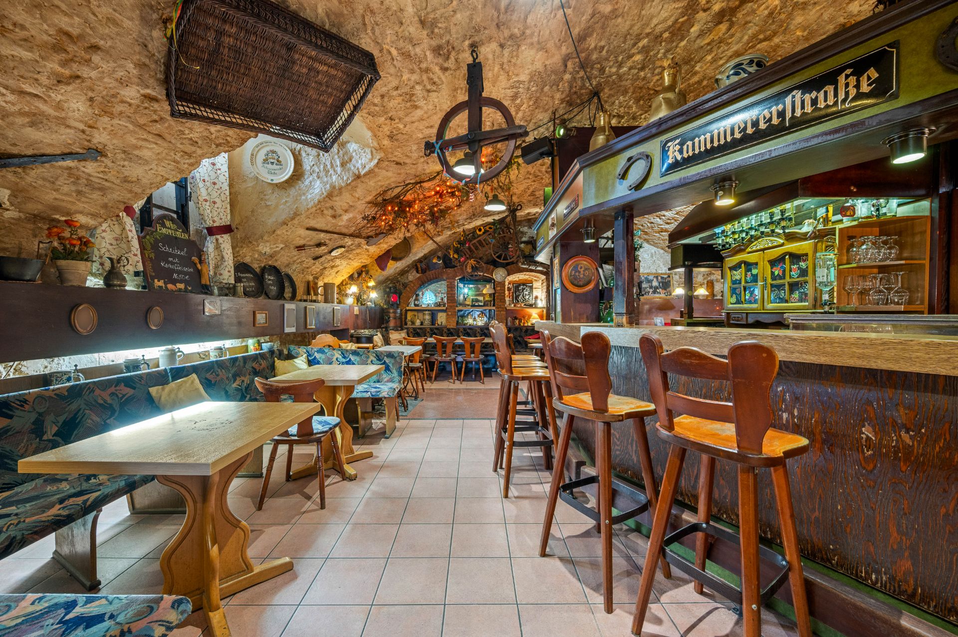Gemütlicher Raum mit steinernen Wänden, Holzmöbeln und Theke im rustikalen Stil.