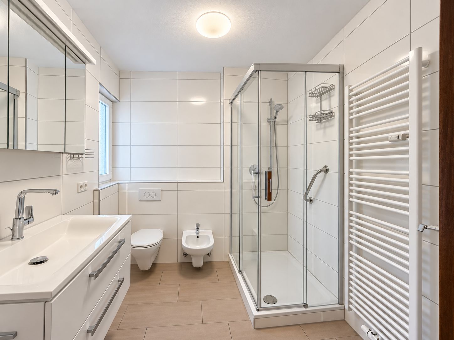 Modernes Badezimmer mit Dusche, Waschbecken, WC, Bidet und Handtuchheizkörper.