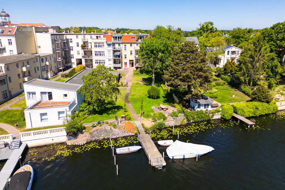 Wohnhäuser mit Garten am Wasser, Bootssteg und kleinen Booten am Ufer.