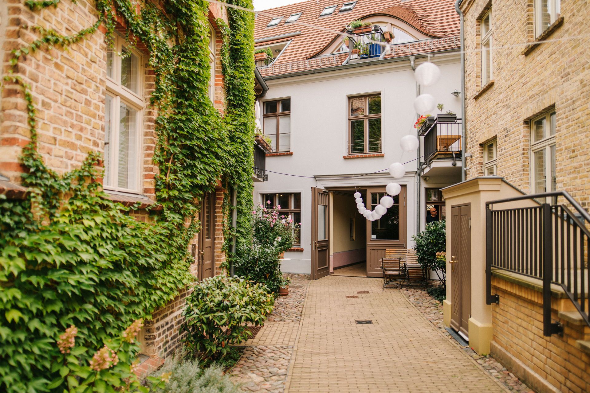 Gepflasterter Innenhof mit Pflanzen, Ballons und umgeben von Backsteingebäuden.