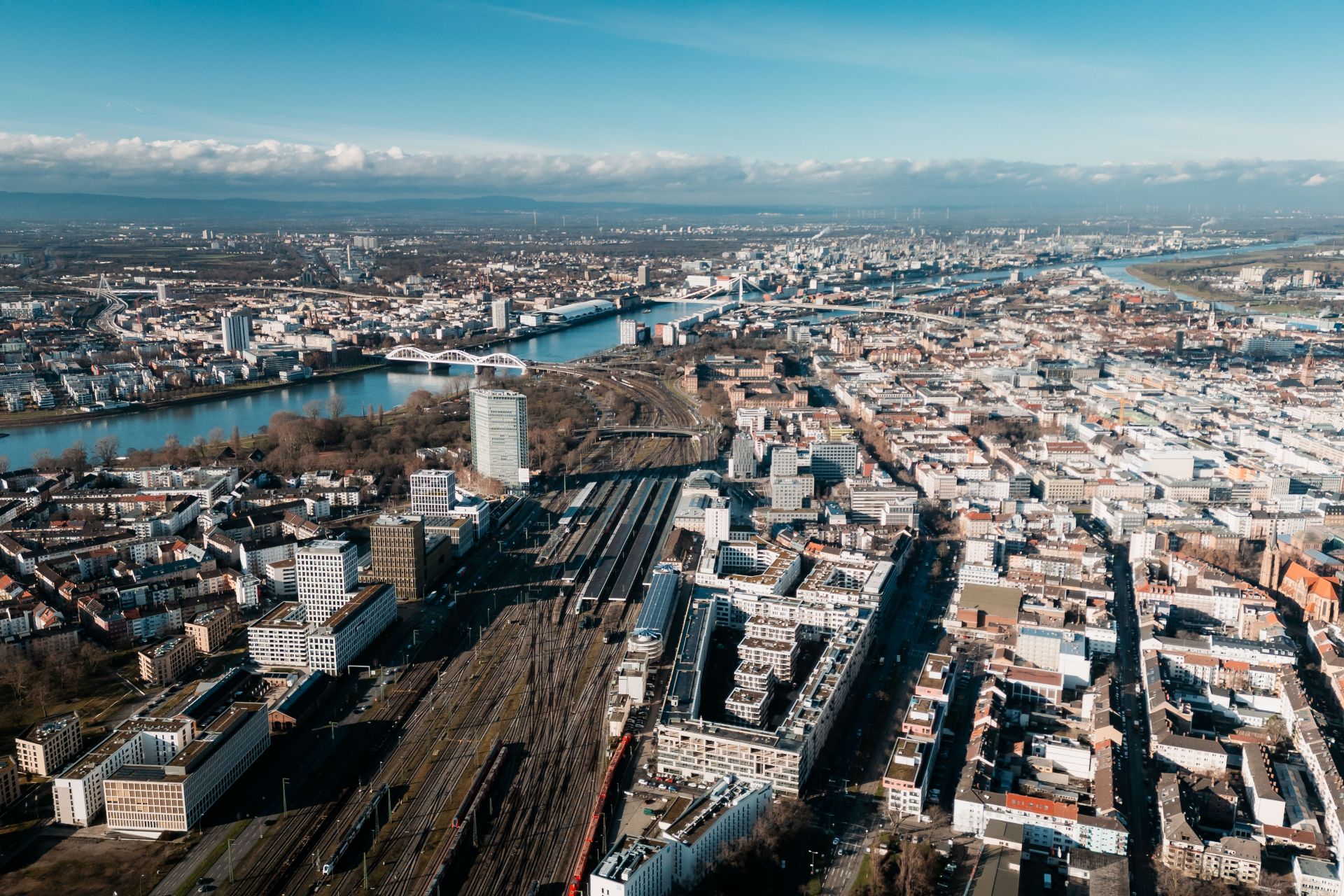 Luftaufnahme einer Stadt mit Fluss, Bahngleisen und vielen Gebäuden.