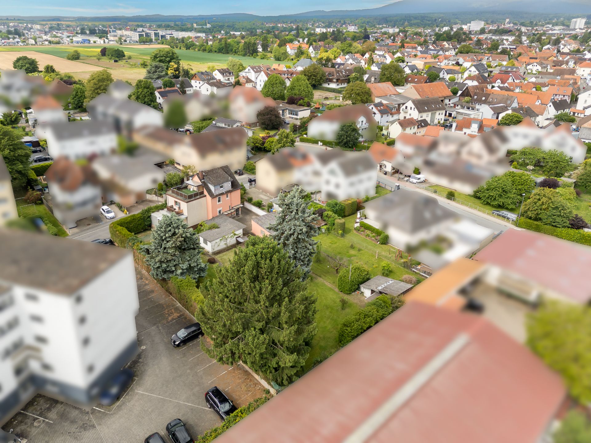 Luftaufnahme von Wohnhäusern mit Gärten und Bäumen in einem Wohngebiet.