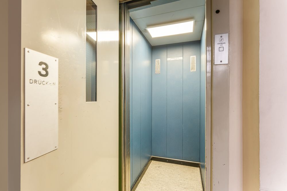 Geöffneter Aufzug mit blauen Wänden und hellem Licht, Tür zeigt Etage 3 an.