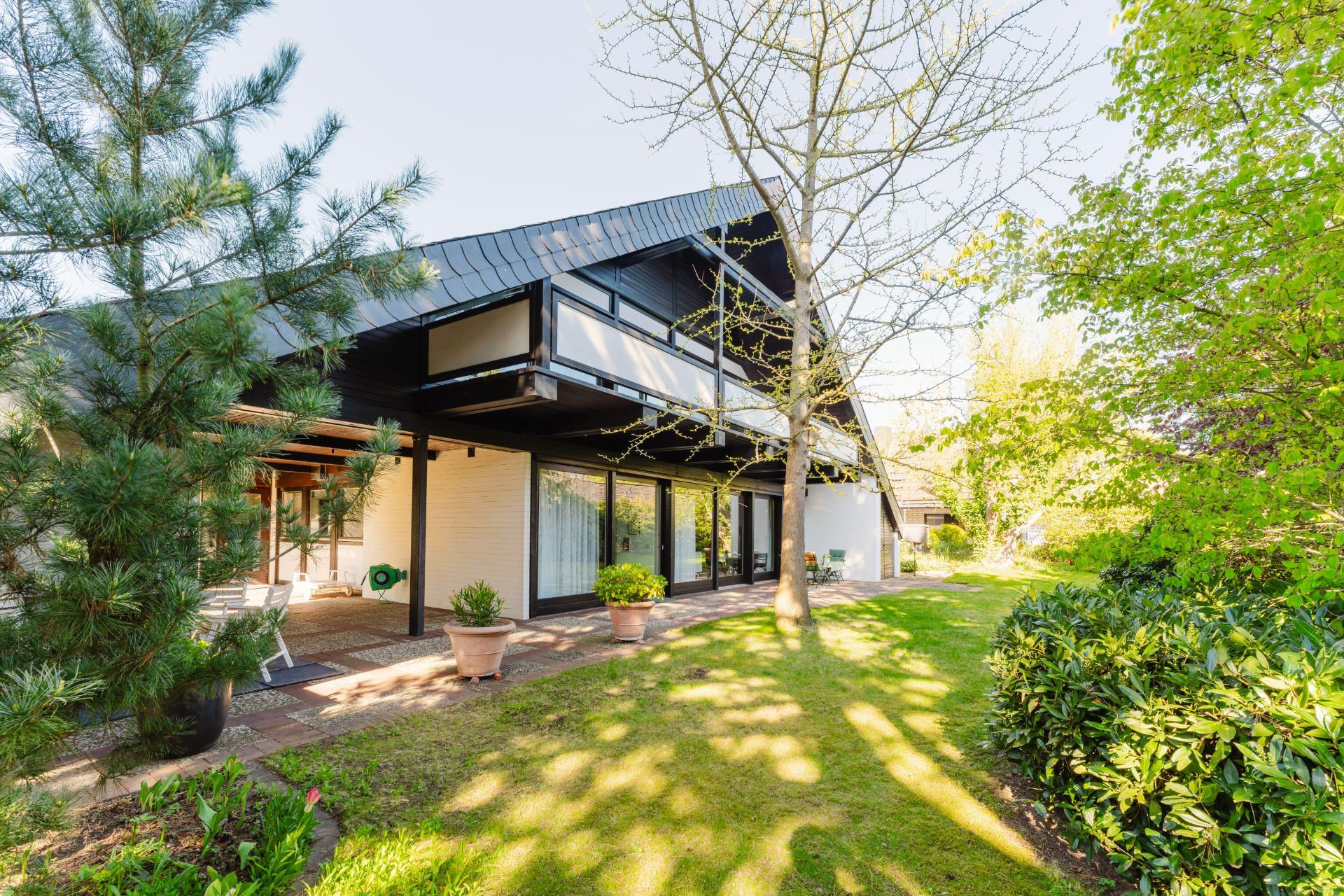 Modernes Wohnhaus mit großer Terrasse, Garten und viel Grün.