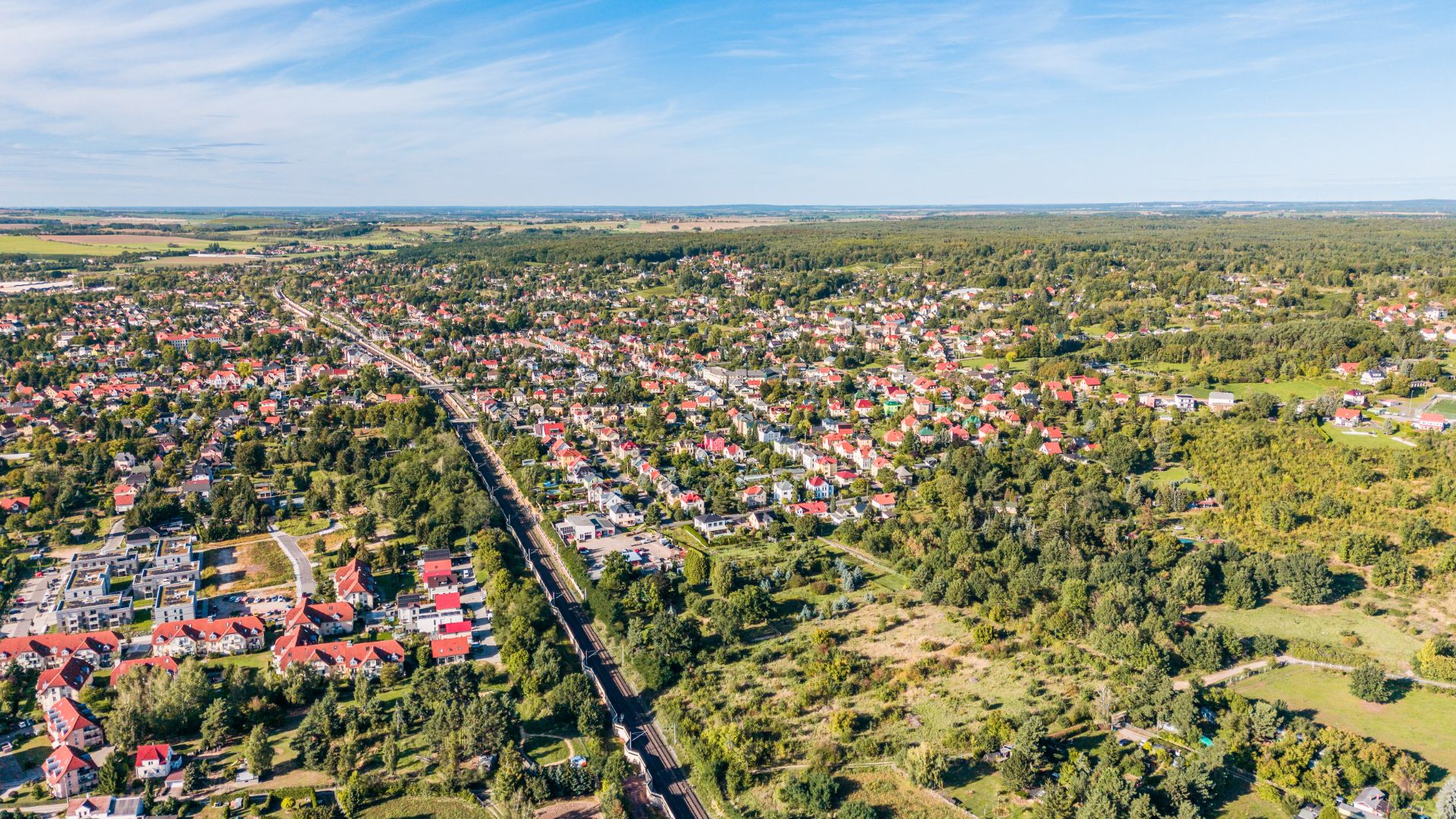 Luftaufnahme einer Wohnsiedlung mit vielen Häusern, umgeben von viel Grün und Bäumen.