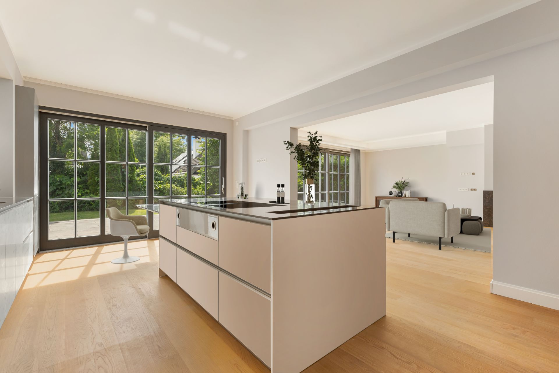 Moderne offene Küche mit Kücheninsel, großen Fenstern und Blick ins Wohnzimmer.