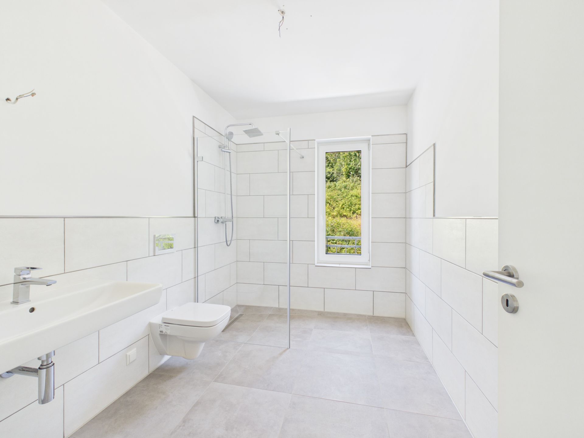 Helles Badezimmer mit Dusche, Waschbecken, WC und großem Fenster.